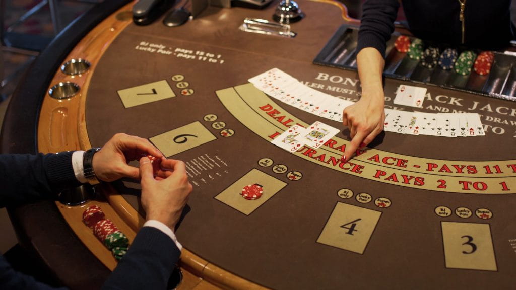 Seorang pengunjung kasino bermain melawan dealer di meja blackjack.