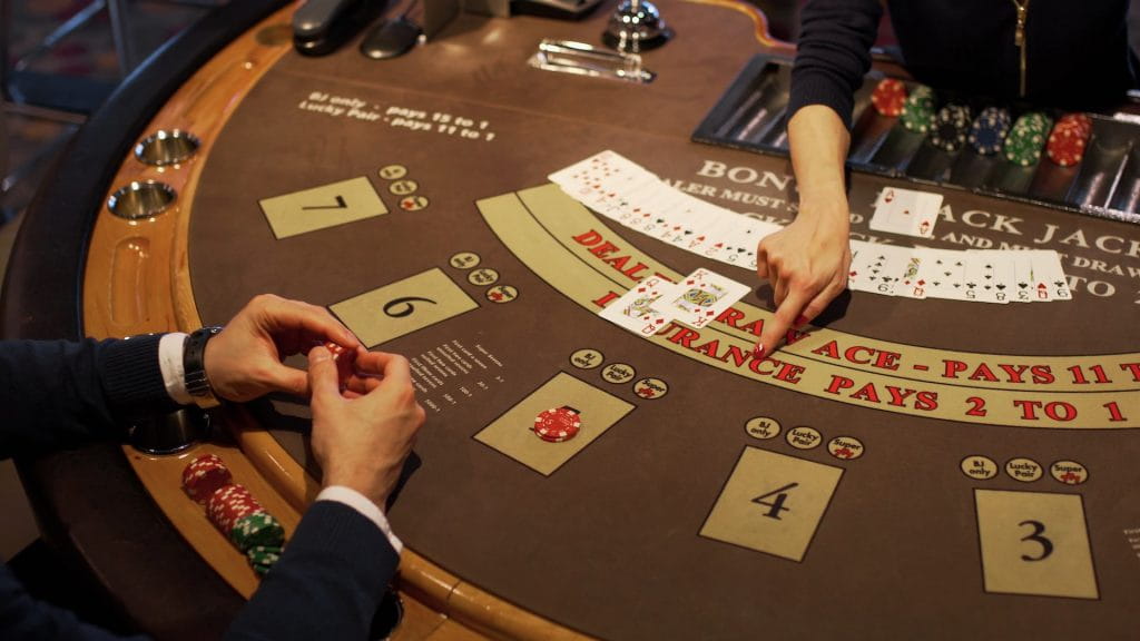 Ein Casinobesucher spielt gegen einen Dealer an einem Blackjack-Tisch.