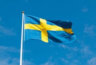 Die Flagge Schwedens an einem Fahnenmast bei wehendem Wind.