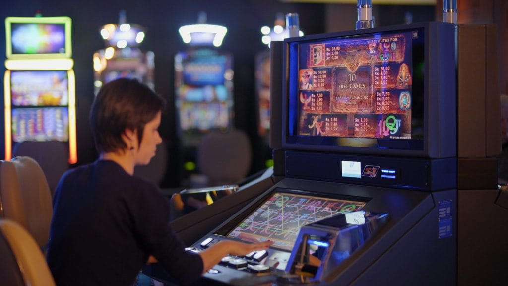 Seorang wanita berjudi di mesin slot Book of Ra di arcade.