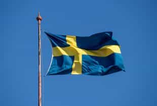 Schwedische Nationalflagge an einem Mast weht im Wind.