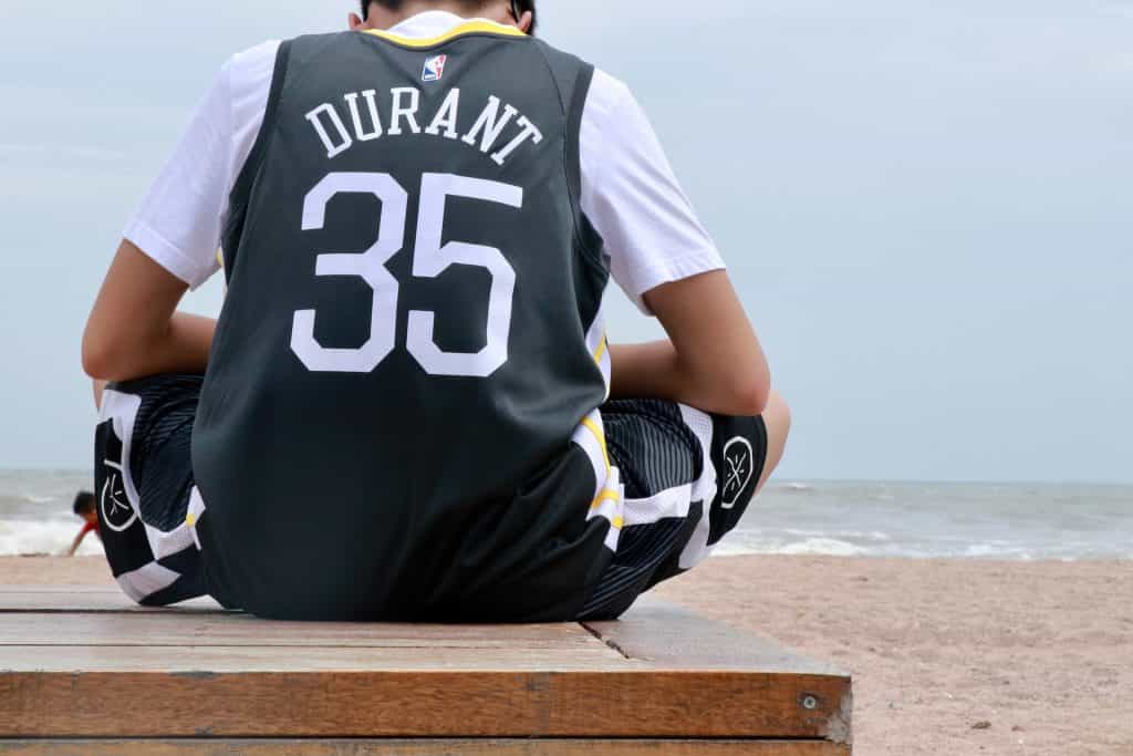 Eine Person mit einem Trikot von Kevin Durant sitz am Meer.