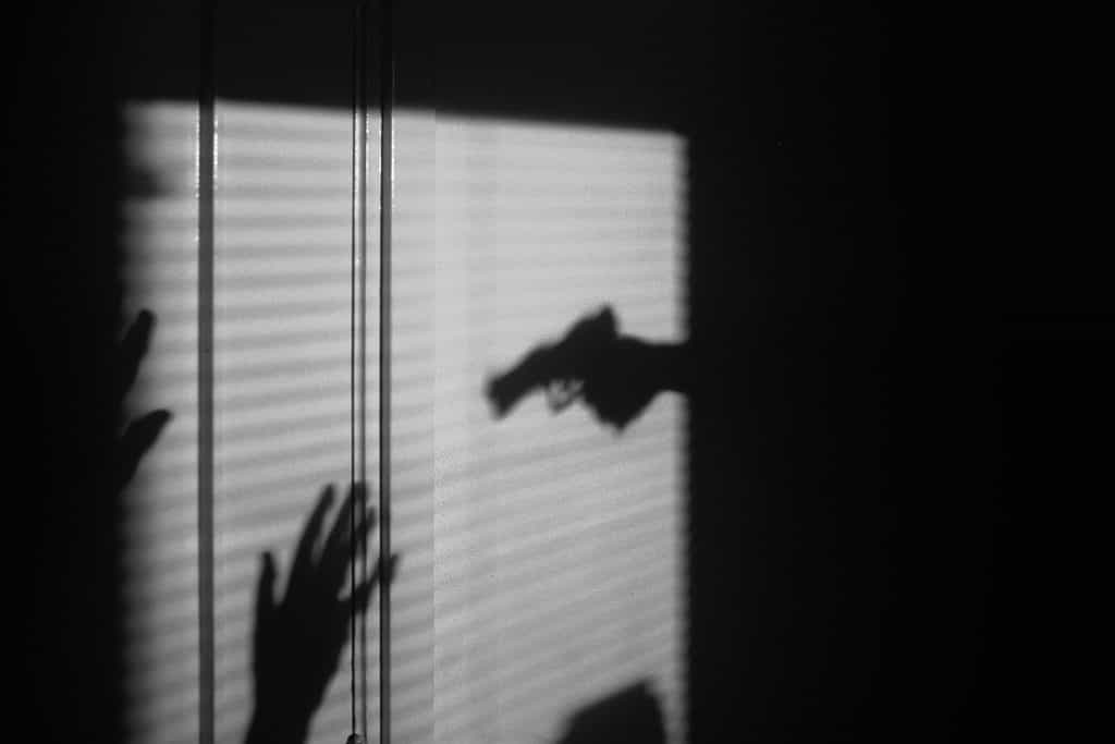 Der Schatten einer Person mit einer Pistole, die ein Opfer bedroht.