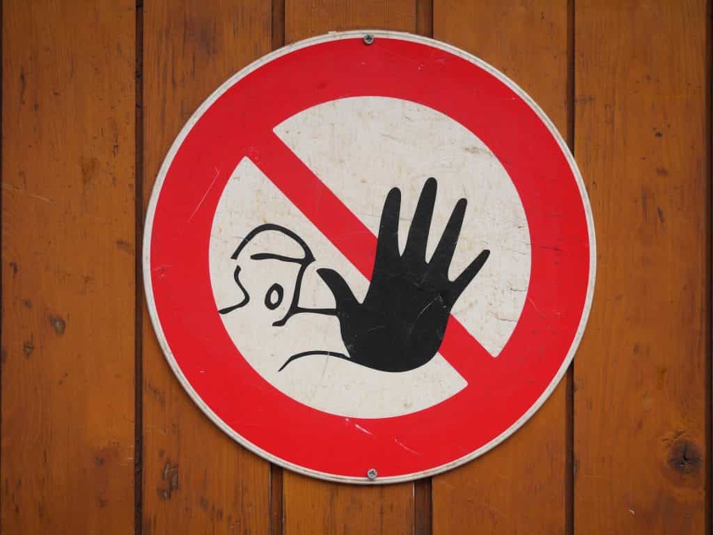 Ein „Betreten-verboten“-Schild hängt an Wand aus Holzpanelen.