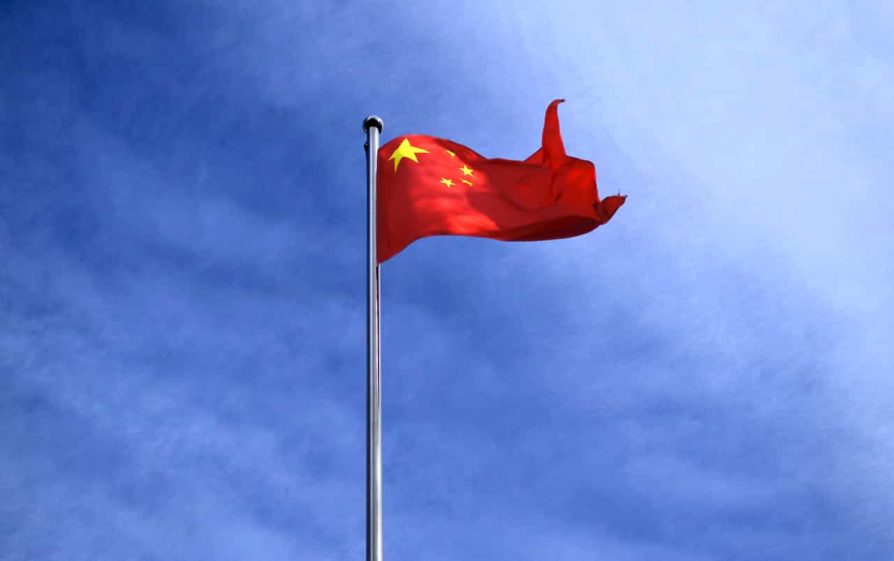Die Nationalflagge Chinas an einem Fahnenmast bei blauem Himmel.