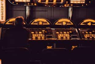 Ein Mann sitzt an Slot-Automaten in einer Spielhalle.