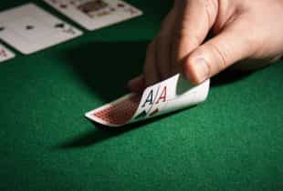 Ein Pokerspieler guckt sich sein Blatt mit zwei Assen an