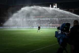 Ein Rasensprenger wässert einen Rasen in einem Fußballstadien