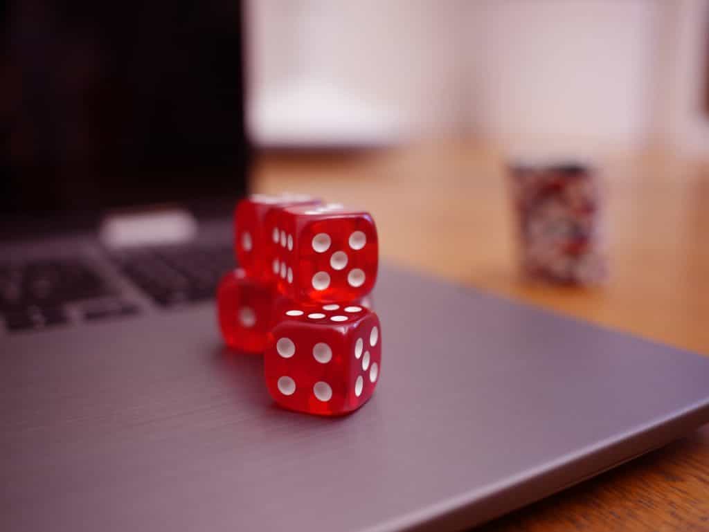 Rote Casinowürfel auf einem aufgeklappten Laptop.