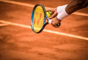 Ein Tennisspieler mit einem Schläger und einem Ball beim Aufschlag.