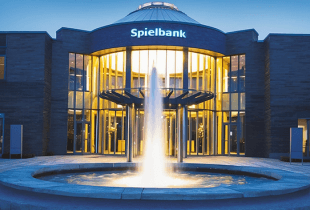 Die beleuchtete Fassade der Spielbank Bad Kötzting bei Nacht, umgeben von einem leuchtenden Garten.