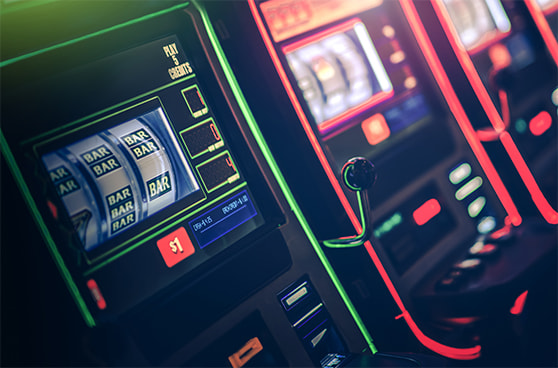 Eine Reihe von Spielautomaten mit blinkenden Lichtern und einem schwach beleuchteten Spielbereich im Hintergrund.