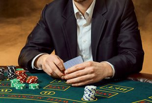 Boris Becker sitzt an einem Pokertisch, umgeben von jungen Pokerspielern.