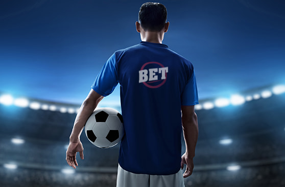 Fußballspieler mit Trikot, das Werbung für einen Wettanbieter zeigt, während ein Stadion im Hintergrund sichtbar ist.