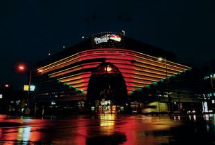 Das Gebäude von Holland Casino in den Niederlanden mit offizieller Beschilderung, im Vordergrund Passanten und ein klarer Himmel.