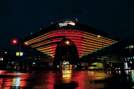 Das Gebäude von Holland Casino in den Niederlanden mit offizieller Beschilderung, im Vordergrund Passanten und ein klarer Himmel.