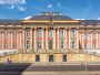Das historische Gebäude des Landtags in Brandenburg bei Tag. Vor dem Gebäude wehen mehrere Flaggen im Wind.